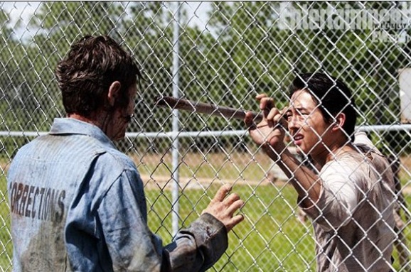 Glenn (Steven Yeun) attempting to kill a walker from behind a fence