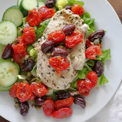 dinner plate with lettuce and cucumber, oven baked chicken breast topped with cooked tomatoes and olives.