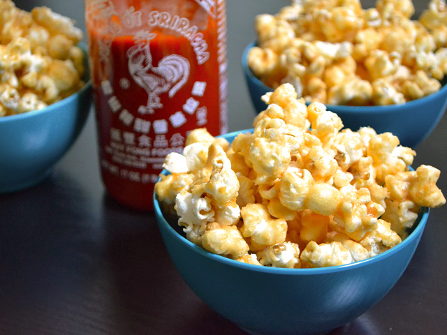 Three bowls of Sriracha Caramel Corn with bottle of siracha 