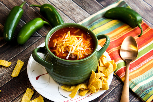 A bowl of Chili with shredded cheese on top.