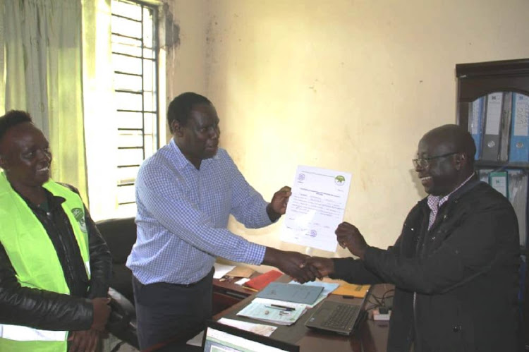 Khwisero ODM MP Christopher Aseka receives his clearance certificate from Khwisero subcounty returning officer Thomas Ng'etich at Khwisero on Monday