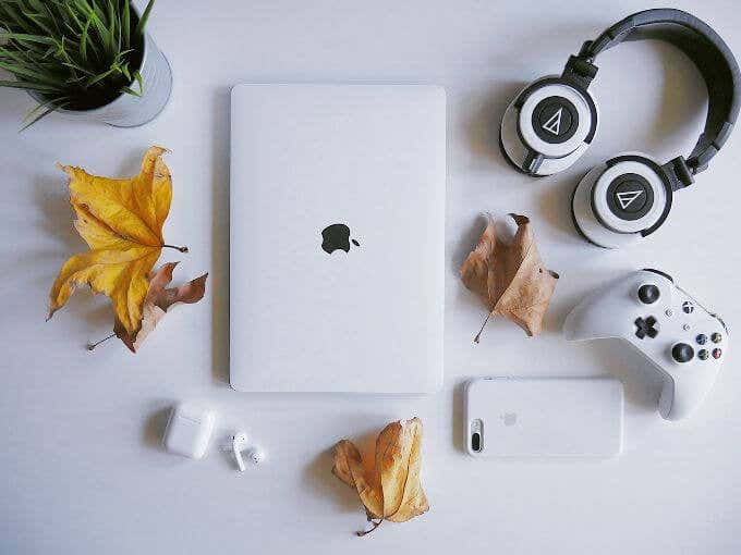 Witte MacBook, iPhone, koptelefoon en gamecontroller op witte tafel