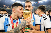 Enzo Fernandez and Germán Pezzella of Argentina kiss the trophy after winning the 2022 World Cup final against France at Lusail Stadium in Lusail City, Qatar on December 18 2022. 