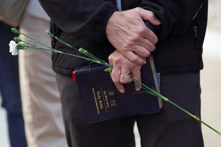 A man holds flowers and a Bible as members of the community hold a prayer vigil near the scene of a shooting that took place during a Chinese lunar new year celebration, in Monterey Park, California, the US, on January 22. Picture: REUTERS/ALLISON DINNER