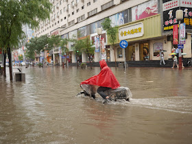 man riding a motorbike on a flooded street in Taiyuan, China