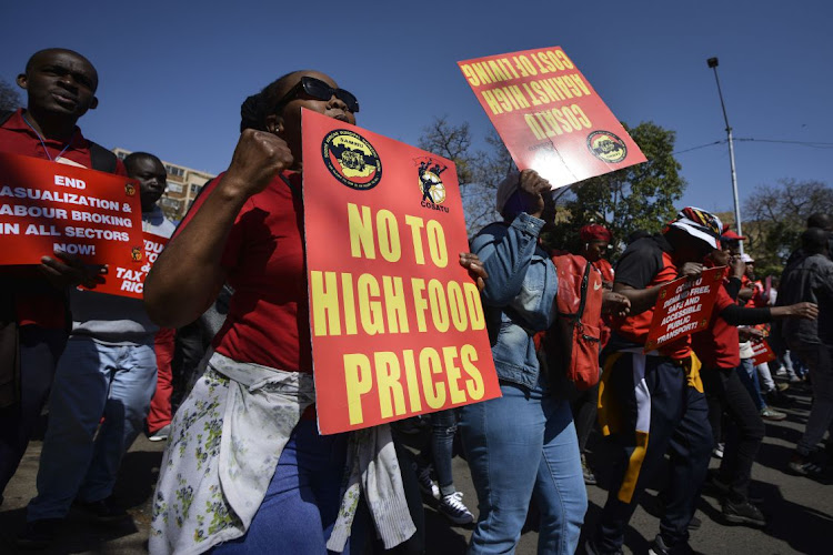 A demonstrator holds a placard reading 'No to high food prices' during a national strike day of action march over the high cost of living in Tshwane.