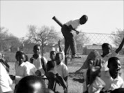 RUNNING SCARED: Pupils as young as seven years had to jump over the fence after scared teachers told them to run for thier lives because they thought a contractor was going to shoot them. Pic. Lazarus Mnisi. 23/09/2008. © Sowetan.