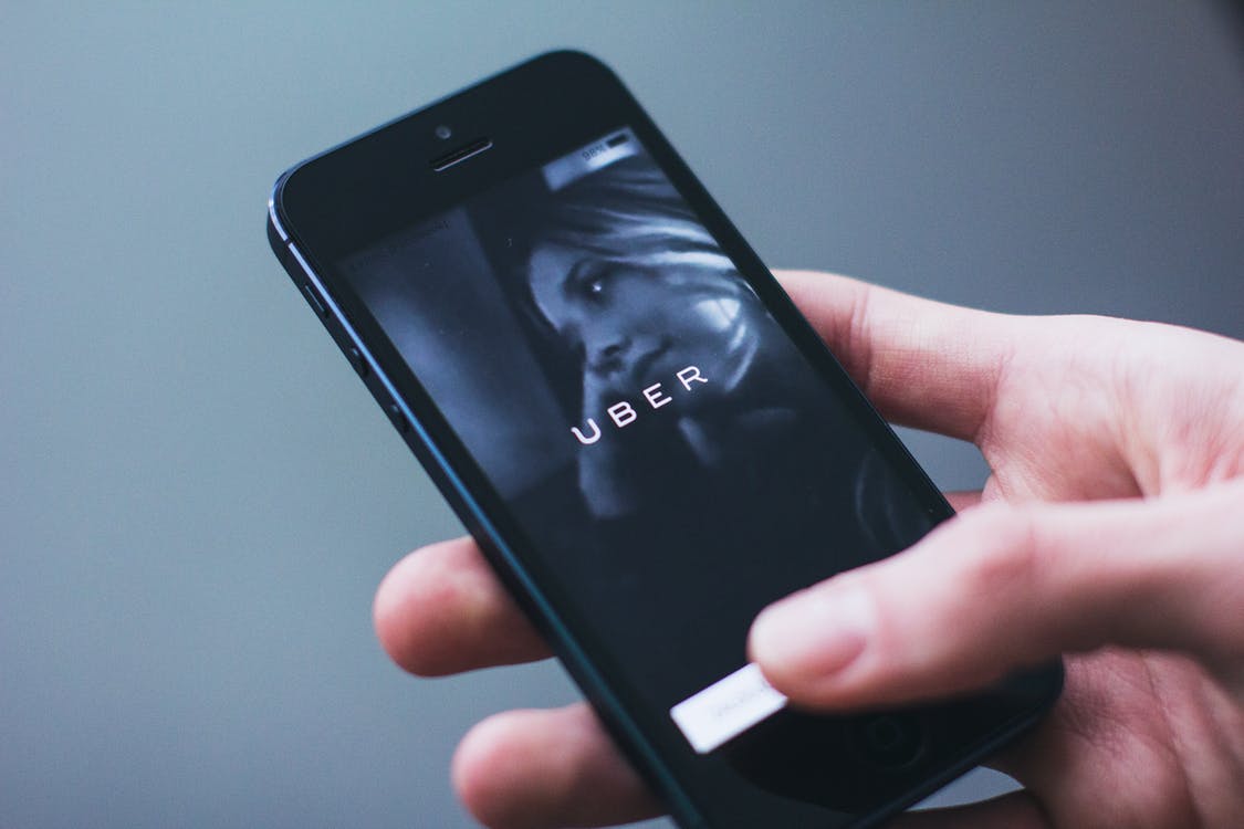 Hand holding a mobile phone, ready to launch Uber app