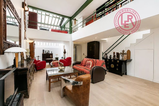 Living room with mezzanine and large bookshelf in this luxury property for sale in Paris 10ème ($1,266,073 - 135 m²)