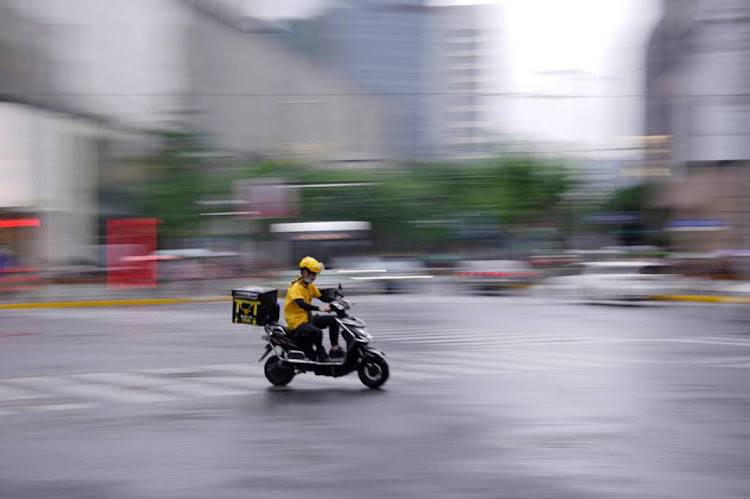 A delivery worker with a face mask rides a scooter on a street in Shanghai, China. File photo: REUTERS/ALY SONG