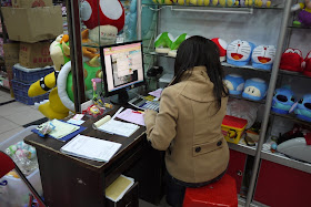 person on the phone and sitting at a computer in a small wholesale store in Guangzhou, Guangdong