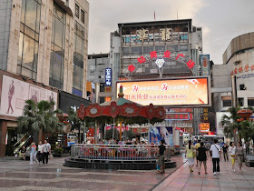 people near a merry-go-round on a pedestrian street in Changde