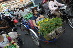 young woman with many flowers riding a pedal-powered rickshaw in Phnom Penh, Cambodia