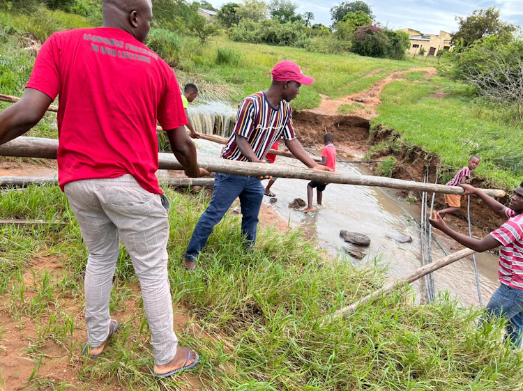 In one of the rural areas most affected by localised flooding in Mpumalanga, residents construct a temporary bridge to help pupils cross to the school on Monday morning.