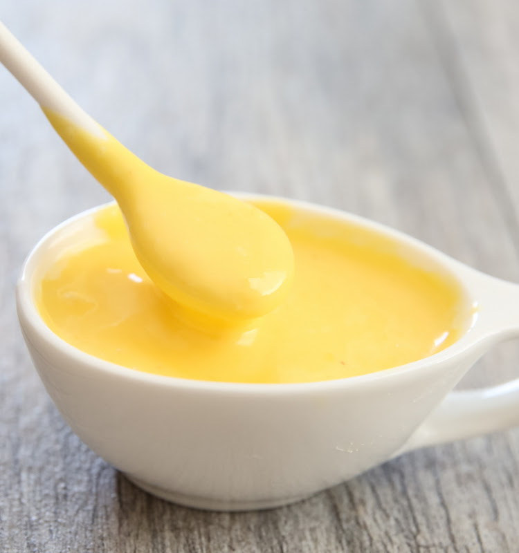 close-up photo of spoon dipping into a bowl of hollandaise sauce