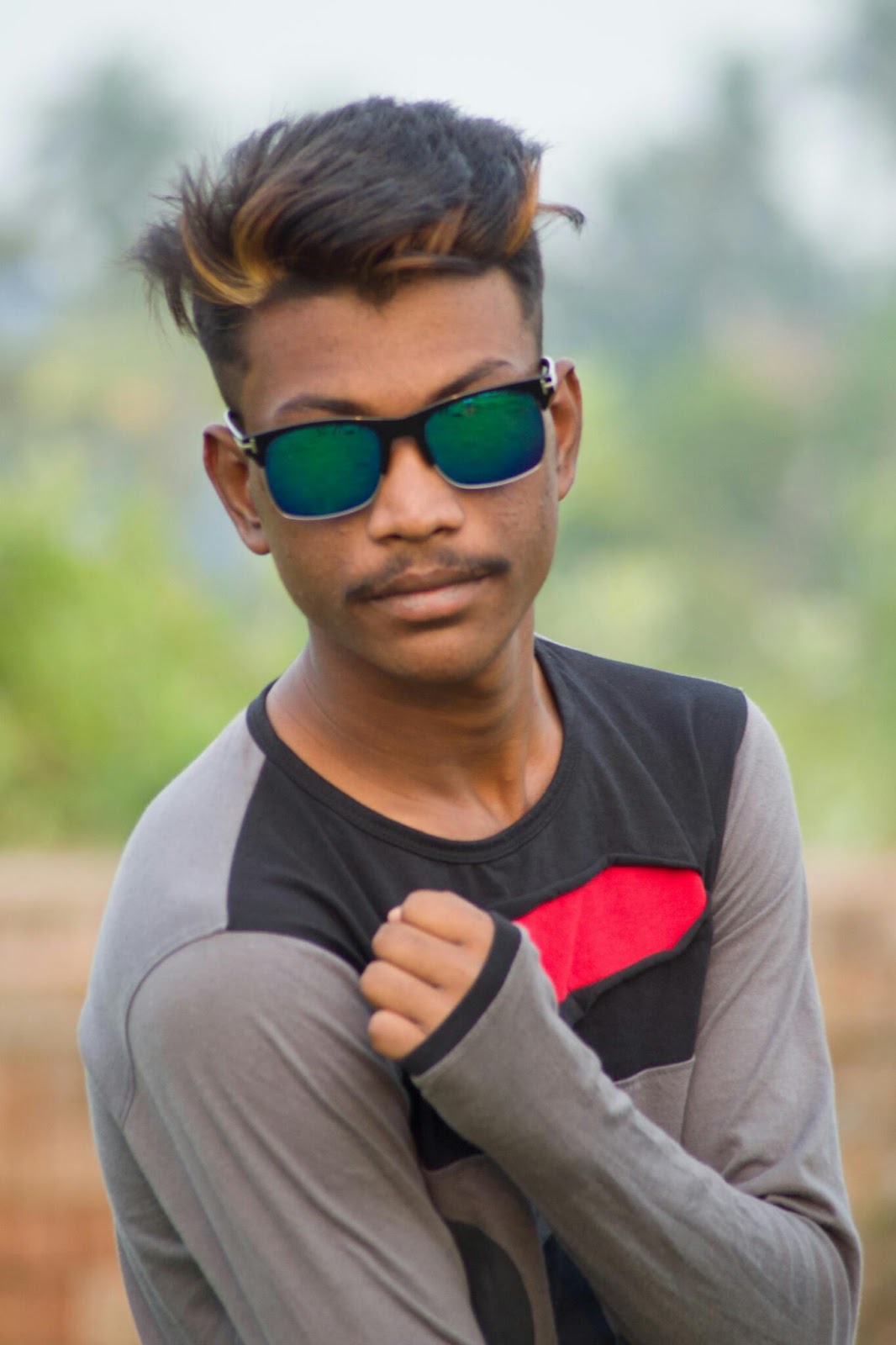 A young boy sitting in a field with a tree in the background photo – Free  Sunglasses Image on Unsplash