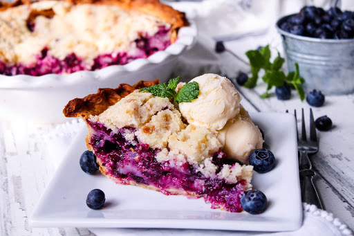 A slice of Blue Berry Cream Pie with two scoops of ice cream.