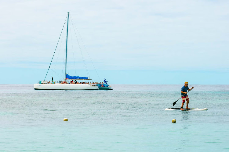 A catamaran and paddleboarder just off West End Beach on Roatan Island, Honduras. 