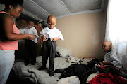 Triplets Reitumetse, Tumelo and Tumisang Mosito are  helped to dress up  by their cousin Kamogelo Mosito in preparation for their first day of school. The four-year-old triplets were born at only six months. / Thulani Mbele