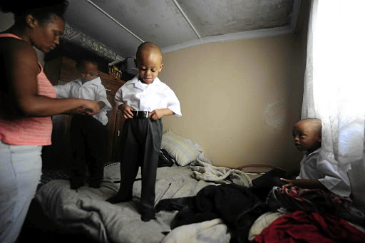 Triplets Reitumetse, Tumelo and Tumisang Mosito are helped to dress up by their cousin Kamogelo Mosito in preparation for their first day of school. The four-year-old triplets were born at only six months. / Thulani Mbele