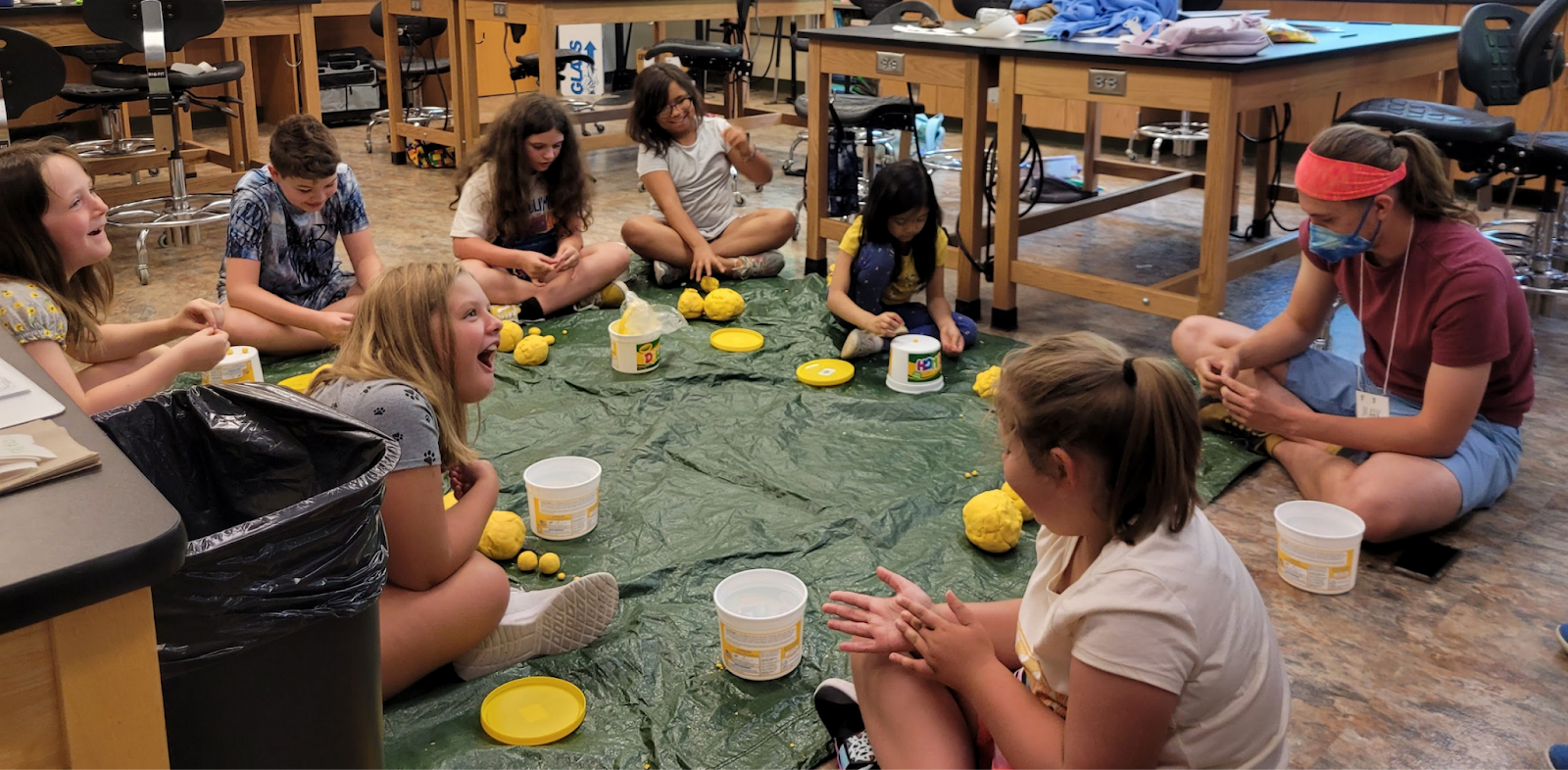 Young students sit in a circle playing with playdough to create planets