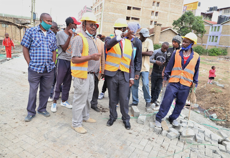 Ruiru MP Simon King'ara (center) with engineers inspecting the ongoing laying of cabroon link roads in Githurai,,Ruiru constituency.