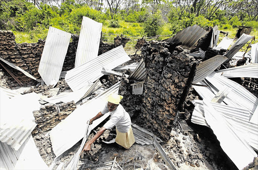 WHEN WILL IT END? A resident rummages through the ruins of her building, which was burnt down after gunmen attacked two coastal towns in Kenya yesterday, killing 29 people