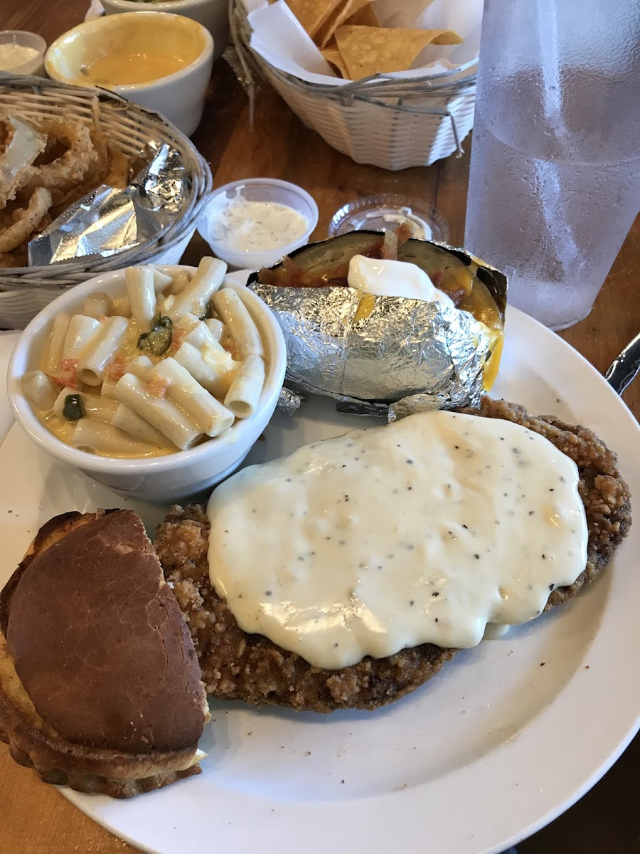 Chicken fried steak with baked potato, Mac and cheese and bread.