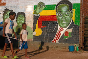 Children walk past a street mural  of  former Zimbabwe president Robert Mugabe   in Harare.  / Tafadzwa Ufumeli/  Getty Images