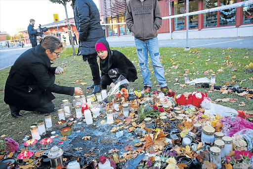 IN MEMORY OF: People light candles in tribute to the victims of an attack outside a school in Trollhattan, Sweden, where a masked attacker armed with a sword and weapons killed a teacher and a boy Picture: EPA