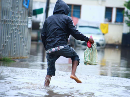 A man wades through a flooded road in Mombasa county as rain pours.Photo / JOHN CHESOLI