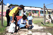 Liyana Gwabeni, 4, at the school gate with his parents Sinethemba and Sphelele Sangweni on Wednesday.