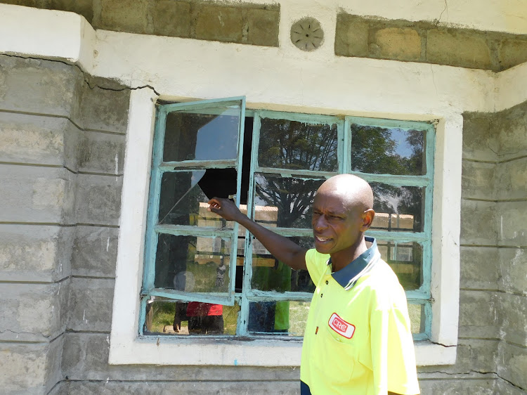 Kaimbaga Primary School management committee chairman Peter Kamau shows a broken window pane