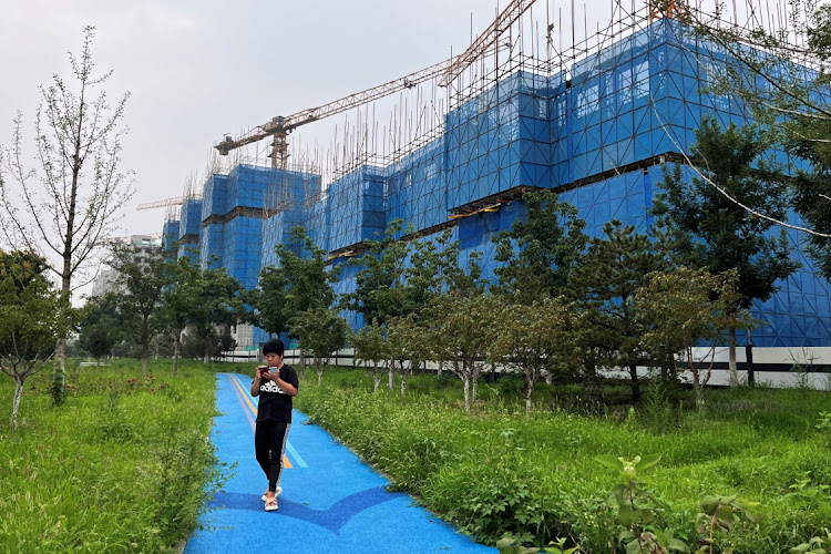 A person walks past a construction site of residential buildings in Beijing, China, August 11 2023. Pictuer: TINGSHU WANG/REUTERS