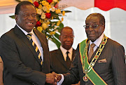 Emmerson Mnangagwa, left, now president of Zimbabwe, shakes hands with   Mugabe at an event in Harare  three years ago.  Picture: Reuters