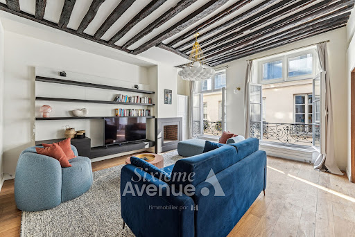 Living room with exposed beams and blue furniture - Buy this luxury property in Paris 1er, 3 rooms, 2 bedrooms