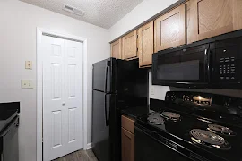 Fully equipped kitchen with wood cabinetry, wood inspired flooring, and black appliances