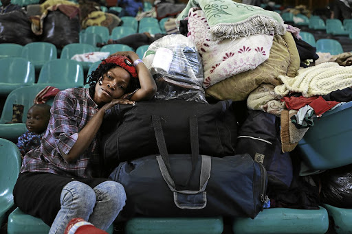 A distraught Mozambican woman waits for help at the DH Willliams Hall in Katlehong, east of Johannesburg, after she was hounded out of her home by militant youths.
