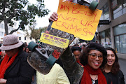 A Cape Town protester holds up a skateboard while taking part in the #TotalShutdown march on August 1, 2018. 