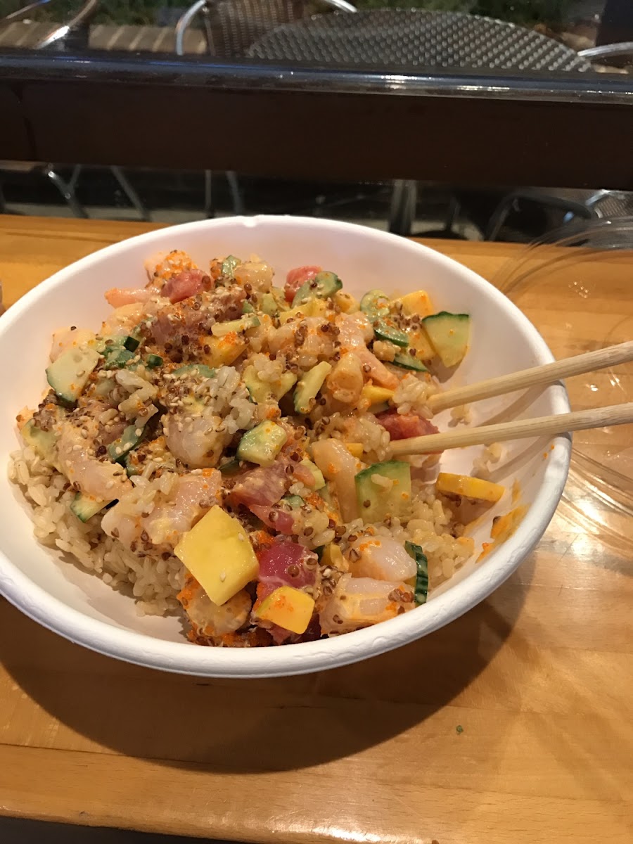 Poke bowl with brown rice, shrimp, tuna, cucumber, mango, quinoa, jalapeños, spicy mayo, sesame seeds, and roe.