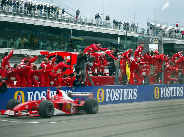 Ferrari pit crew celebrate Michael Schumacher securing first place at the 2003 USA Grand Prix in the F2003-GA.