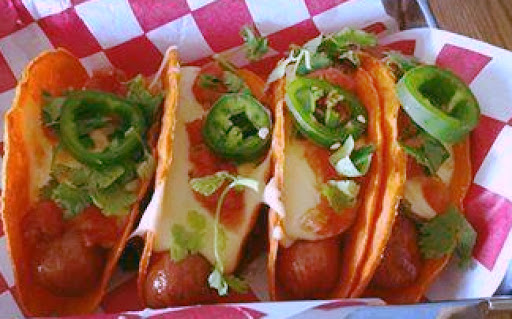 hot dogs in taco shells with cheese and condiments