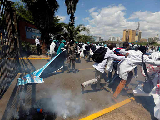 Doctors run, after riot police fired tear gas canisters to disperse them, during a demonstration in Nairobi to demand fulfillment of a 2013 agreement between their union and the government, December 5, 2016. /REUTERS