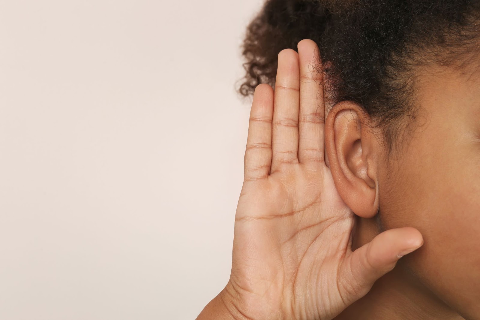 african american woman using her right hand to push her forward so she can hear better