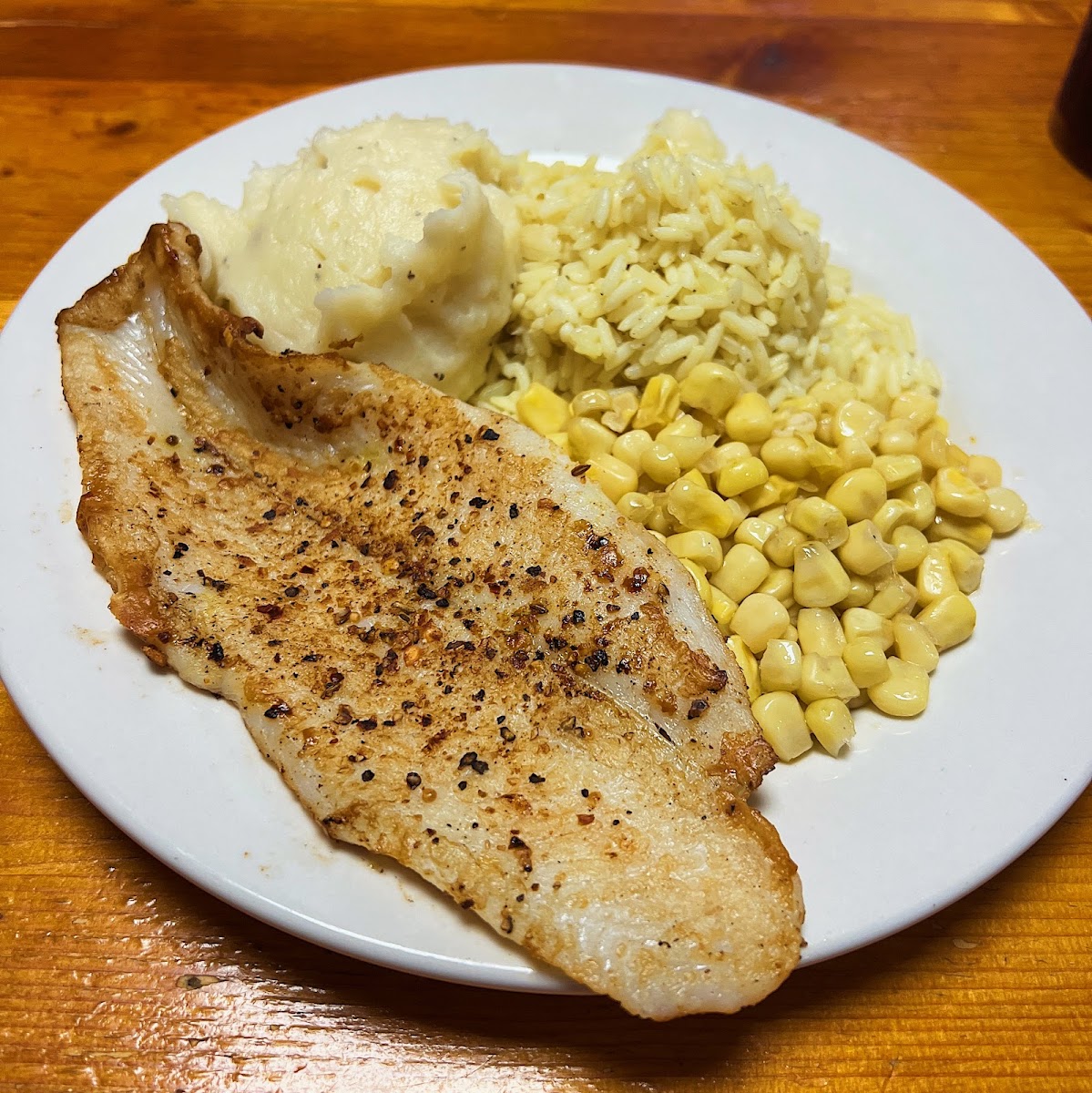 Grilled fish, mashed potatoes, rice, and corn