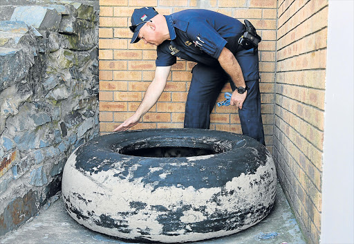 FLYING FANCY: Warrant Officer Pierre Marx inspects a tyre discovered between Nahoon and Bonza Bay beaches Picture: ALAN EASON