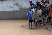 People stand next to a flooded area as Cyclone Batsirai sweeps inland in Fianarantsoa, Madagascar, on February 6 2022.