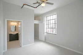 Bedroom with attached bathroom, featuring very large walk in closet, large picture window, grey walls, white trim