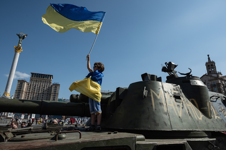 A boy holds a Ukrainian national flag as he stands on top of a Russian military vehicles displayed in the downtown area on August 21 2022 in Kyiv, Ukraine. Picture: GETTY IMAGES/ALEXEY FURMAN