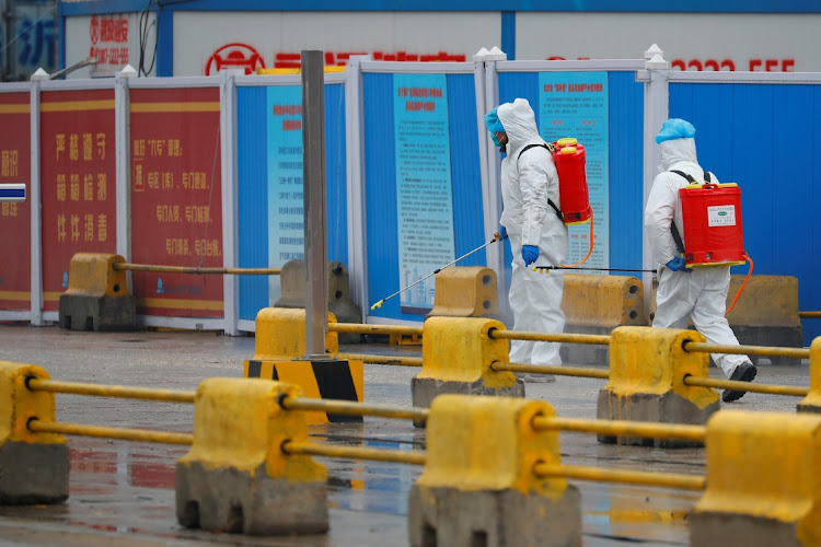 Workers in PPE spray the ground with diinfectant in Baishazhou market during a visit of World Health Organization (WHO) team tasked with investigating the origins of the coronavirus (Covid-19) pandemic, in Wuhan, Hubei province, China, January 31, 2021.